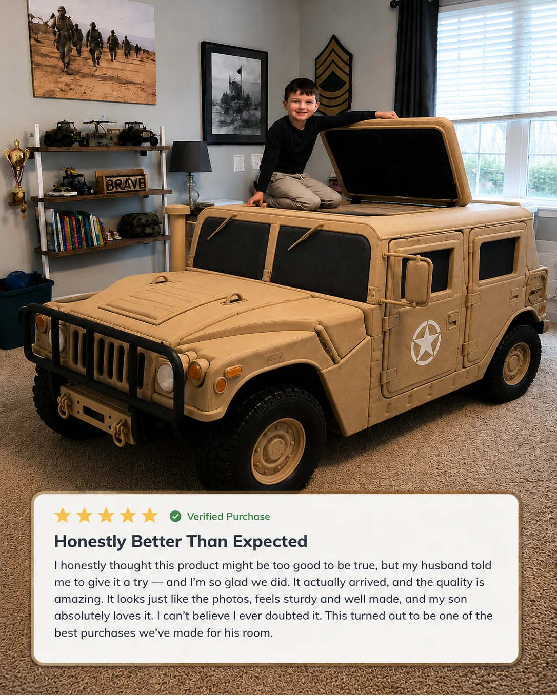 A child sits on top of a large tan military-style toy vehicle in a home office or playroom. The vehicle has black windows, a front grille, wheels, and a white star emblem on the side.
