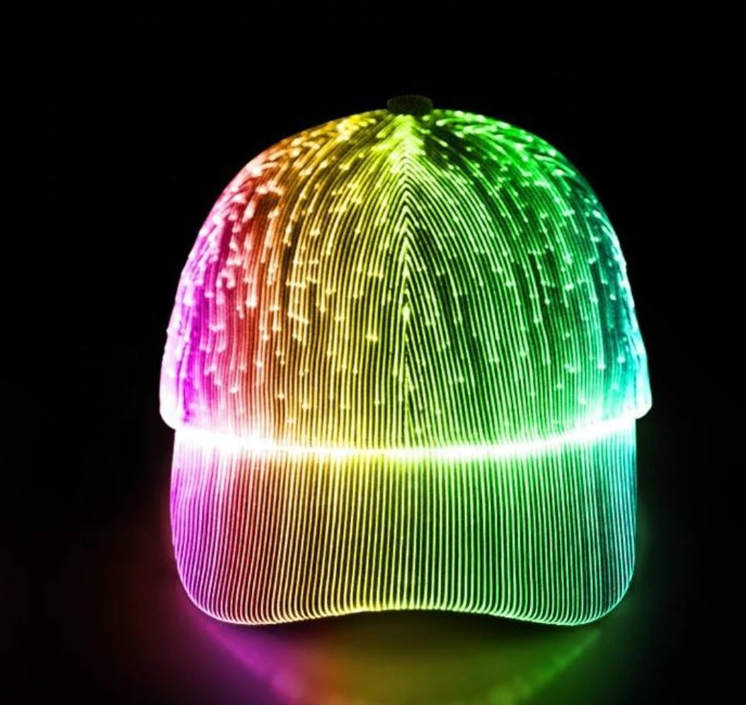 A baseball cap covered in glowing LED fiber-optic strands, displaying a vibrant rainbow gradient of colors against a solid black background.