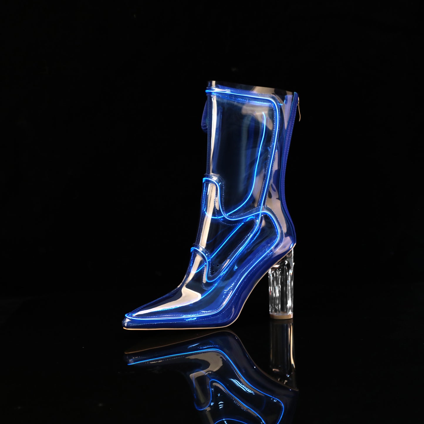 A single transparent knee-high Cowboy LED boots with a pointed toe and clear block heel, shown on a black reflective surface against a black background. The boot has bright blue neon-like outline lighting along its edges.