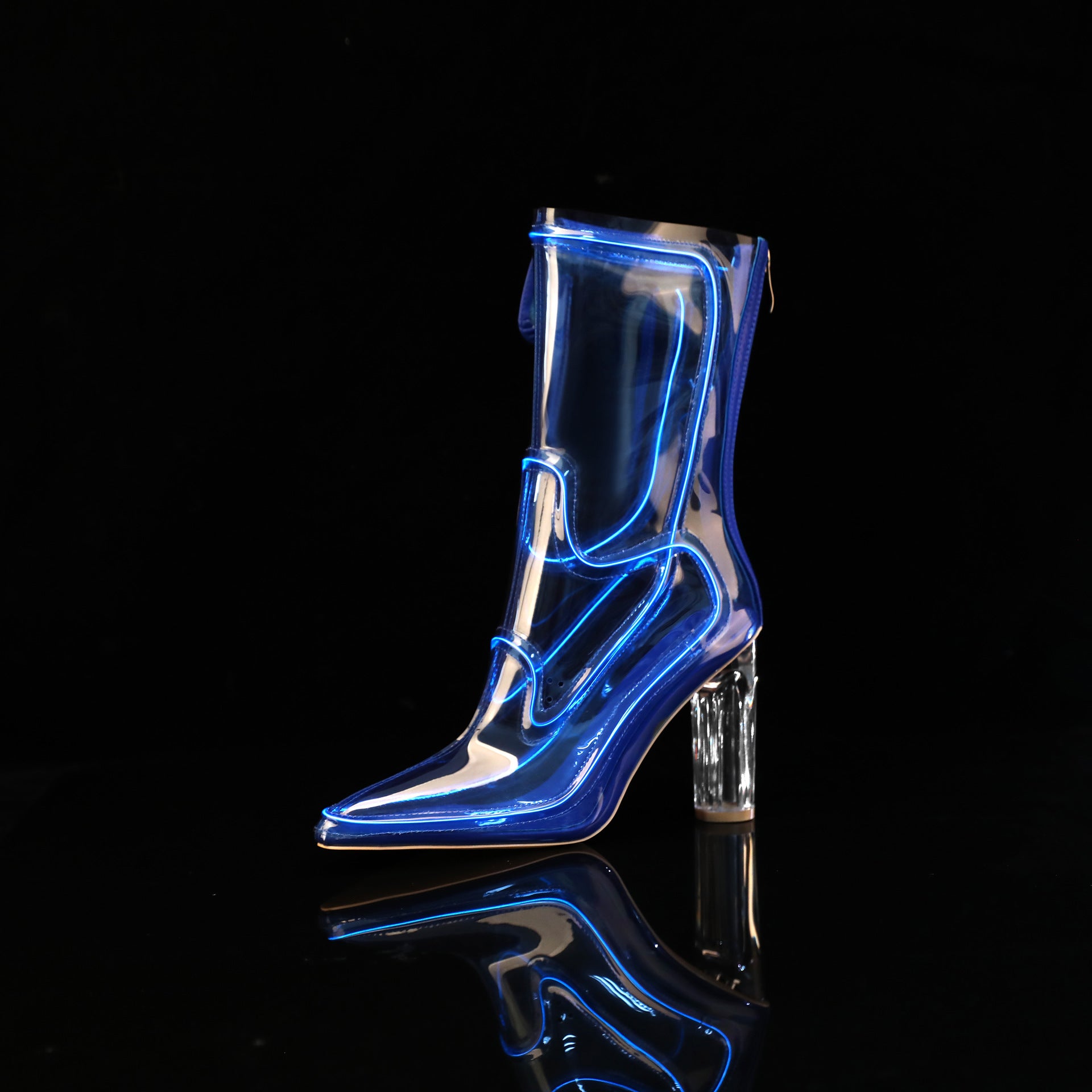 A single transparent knee-high Cowboy LED boots with a pointed toe and clear block heel, shown on a black reflective surface against a black background. The boot has bright blue neon-like outline lighting along its edges.